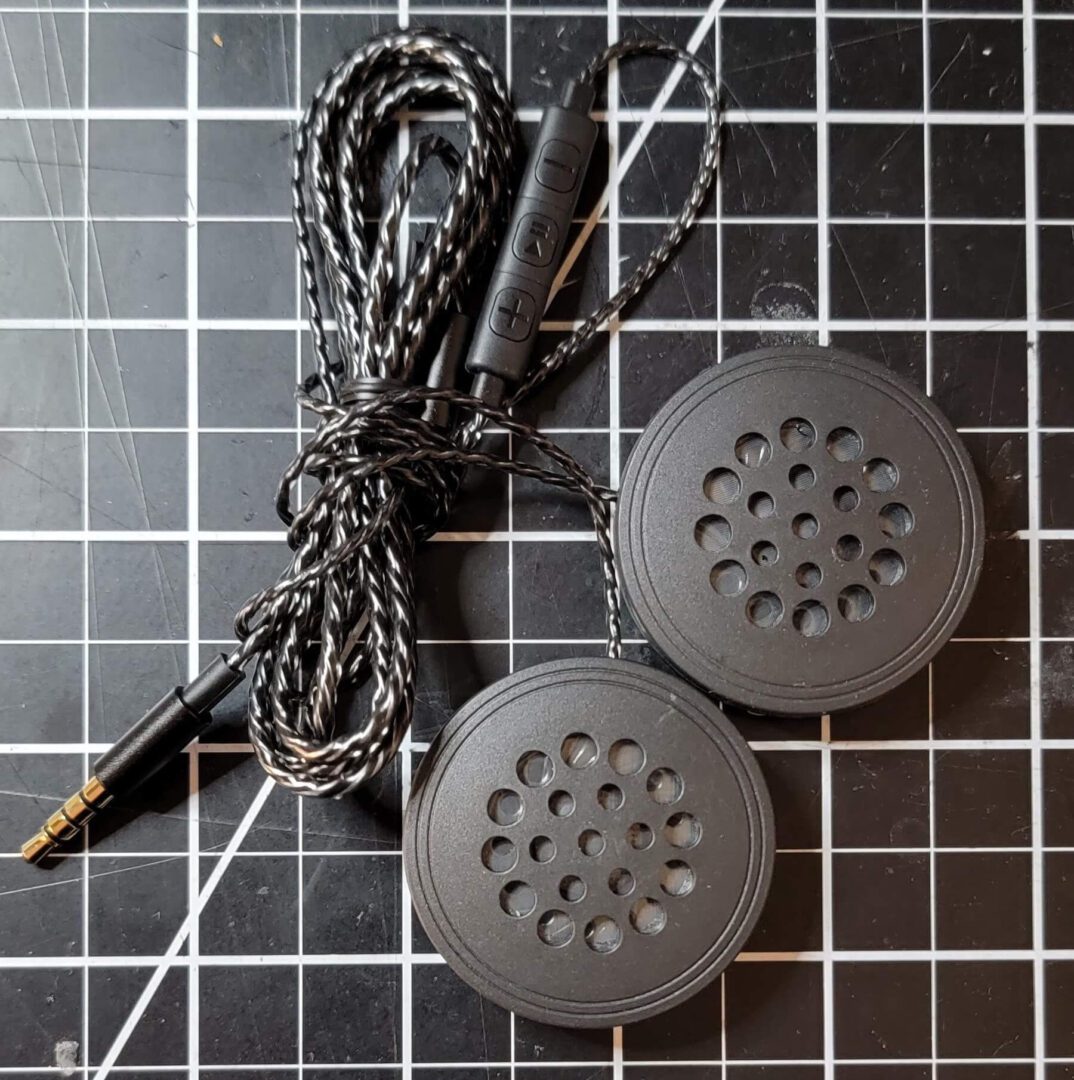 A pair of earbuds and a cord on a black tile floor.