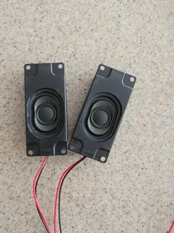 Two speakers are sitting on the floor with wires.