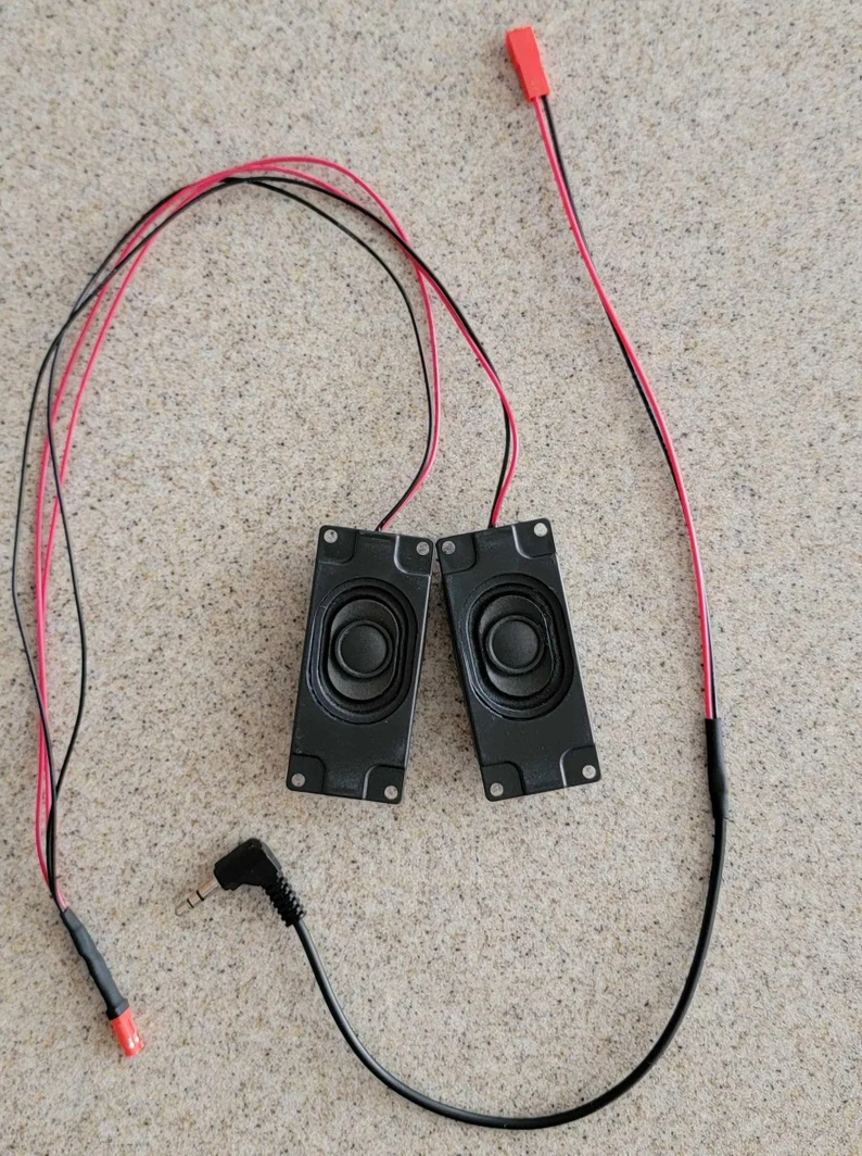 A pair of speakers and wires are laying on the floor.